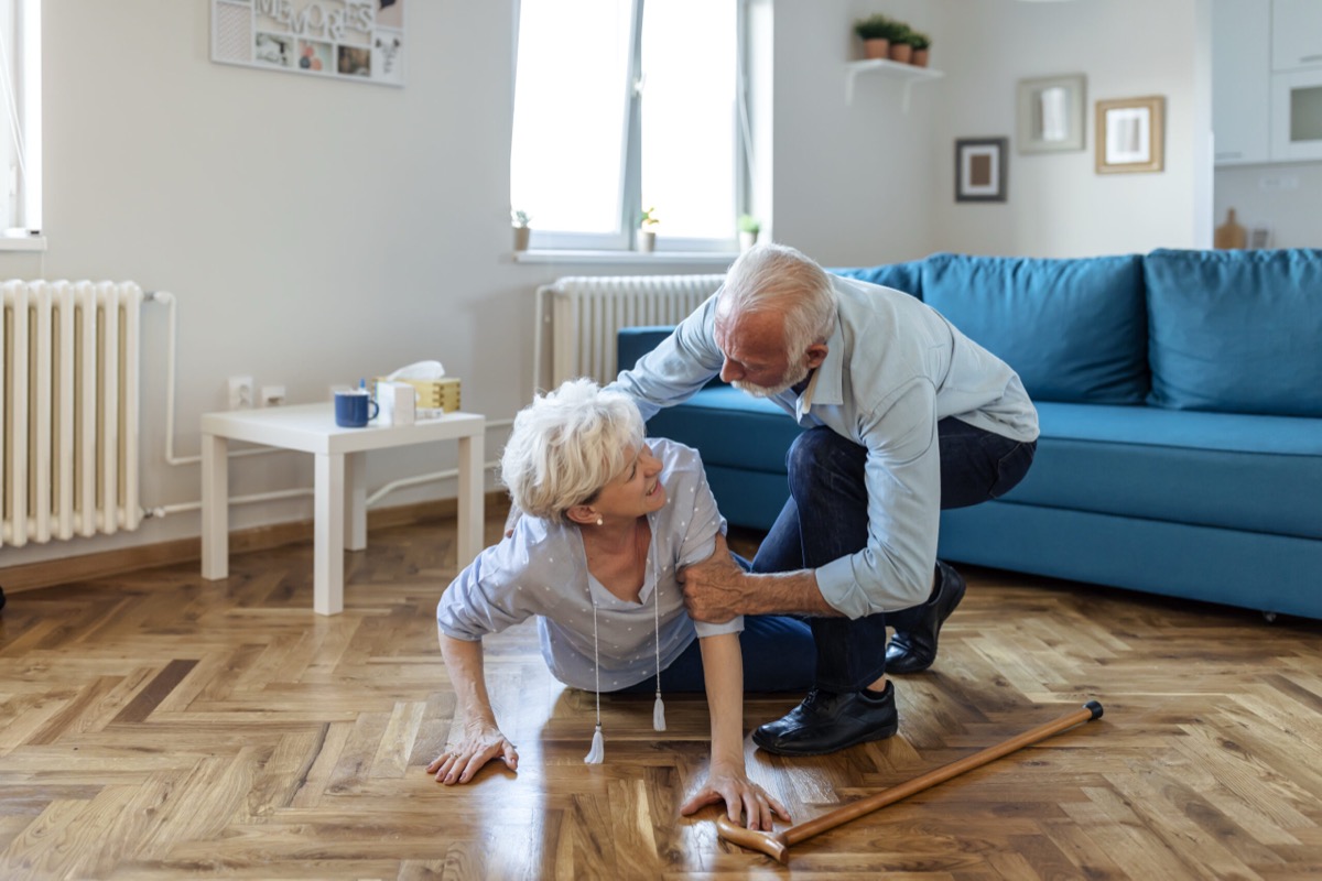 An older man helping an older woman up after a fall at home