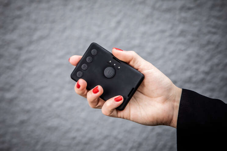 Hand holding a compact wireless panic button used with a home alarm system