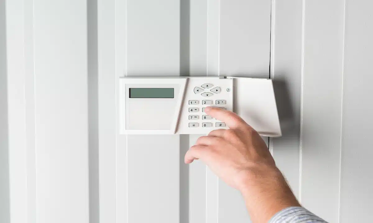 Person entering a code on a wall-mounted home alarm keypad
