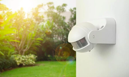 Outdoor motion-sensor light mounted on an exterior wall above a garden