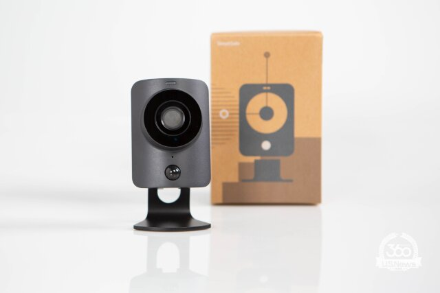 A SimpliSafe continuous recording camera stands prominently in front of its brown packaging. 